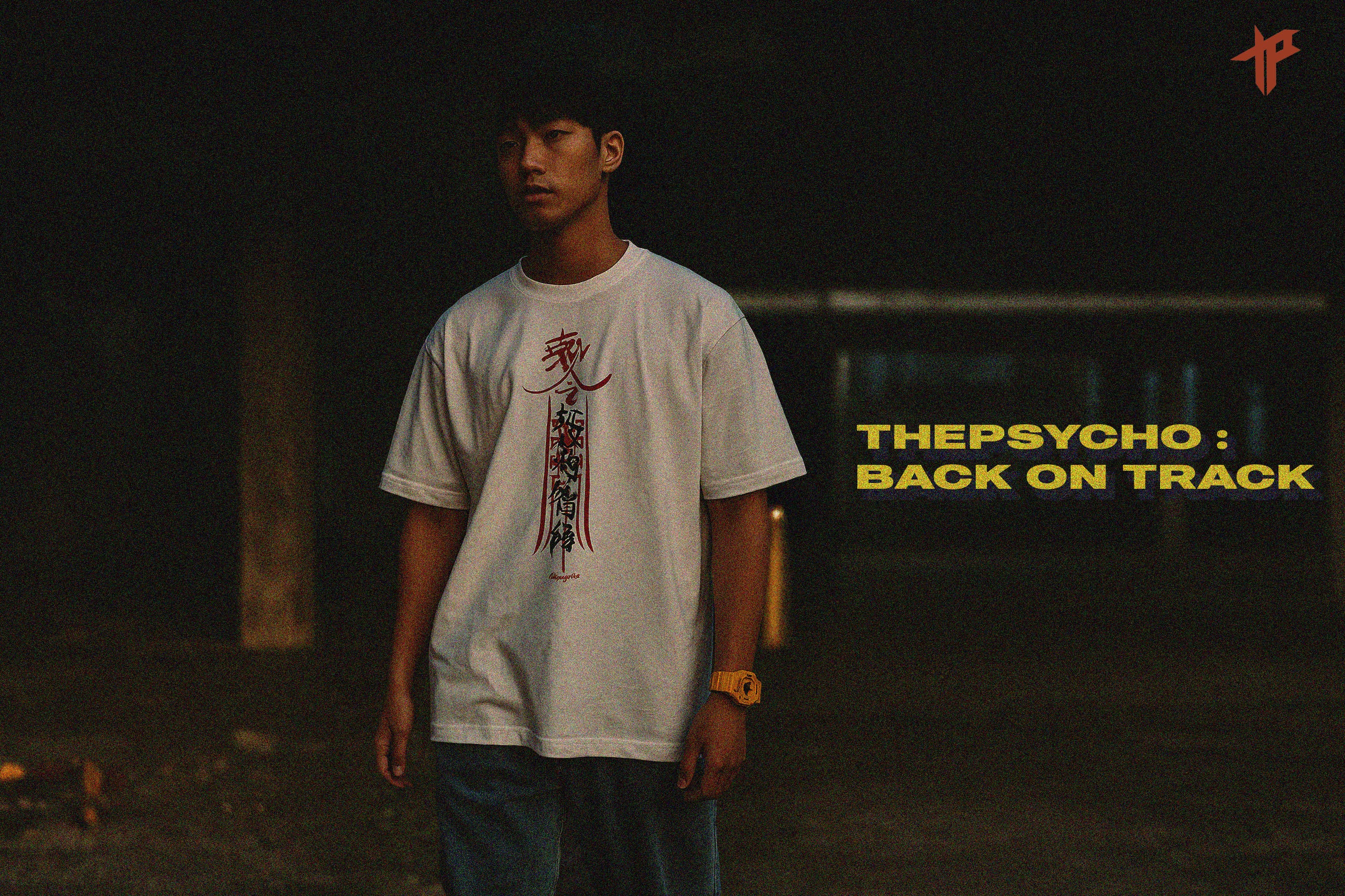 Person wearing a white t-shirt with text in a dark setting, featuring 'THEPSYCHO: BACK ON TRACK' text.